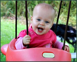 Laughing baby girl in a baby swing