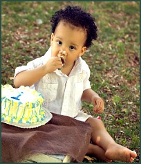 Baby boy outside eating his birthday cake