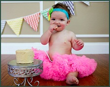 Baby girl in a tutu sampling her birthday cake