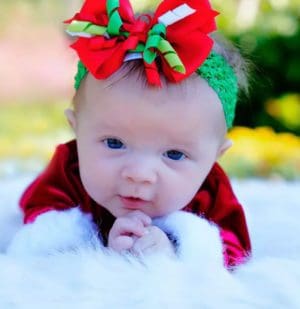 Baby girl dressed in a Christmas outfit and bow