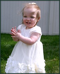 Happy baby girl in a dress claps her hands
