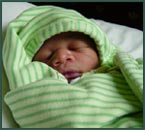 Sleeping baby swaddled in a green striped blanket