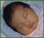 baby sleeping on striped pillow