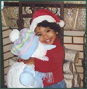 Little girl in a Santa hat hugs a snowman stuffed animal
