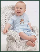 Happy baby boy sitting in white wicker chair
