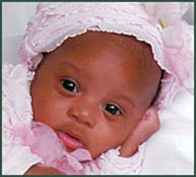 Black baby girl in a frilly pink bonnet
