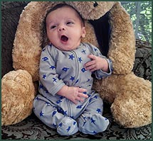 Yawning baby boy with a huge teddy bear