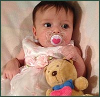 Baby girl with a pacifier and teddy bear