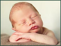 Sleeping baby with arms crossed and head resting on arms