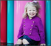 Little girl in a bright purple coat beaming from ear to ear