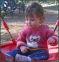 Girl on swing with cat sweater on
