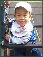 Black baby boy in a swing at the park