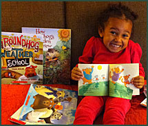 Little girl beams amongst her Groundhog Day books