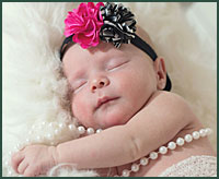 sleeping baby is posed for the camera with necklace