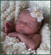 Baby asleep in white furry blanket with white flower headband
