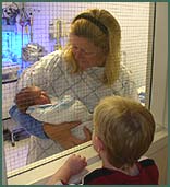Adoptive mother shows her son a glimpse at his new brother from the hospital nursery