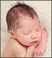 Sleeping newborn baby boy posed with his head on his arms
