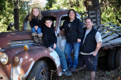 Family of four posed by an old pickup truck