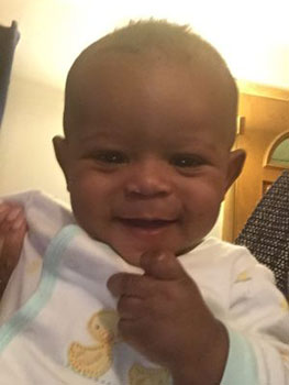 Close up of a black baby boy playing with his bib