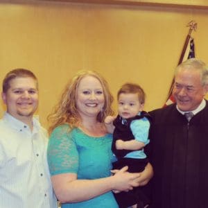 Happy couple pose with judge at son's adoption finalization