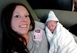 Smiling adoptive mother holds her newborn baby