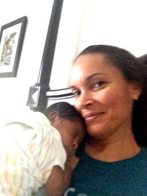 Happy adoptive mom smiles as her baby sleeps on her chest