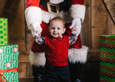 Redheaded little boy holding Santa's hands
