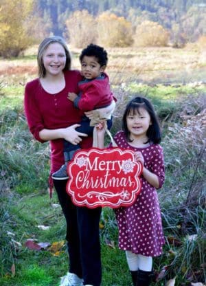 Three smiling children hold a Merry Christmas sign