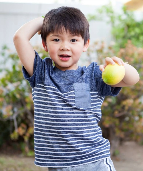 Asian boy in a striped shirt holding a lemon