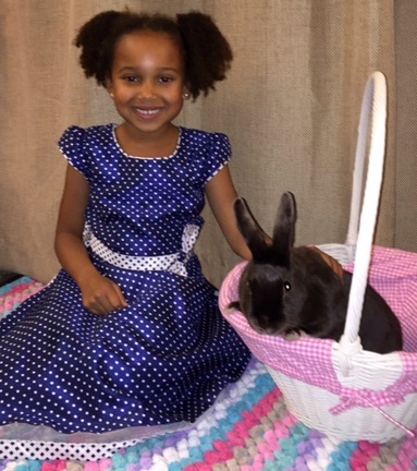 young girl poses with a live bunny in an Easter basket