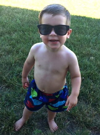 Caucasian little boy in sunglasses and swim trunks