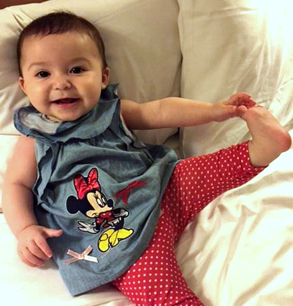 Baby girl with Minnie Mouse shirt on holds her own foot
