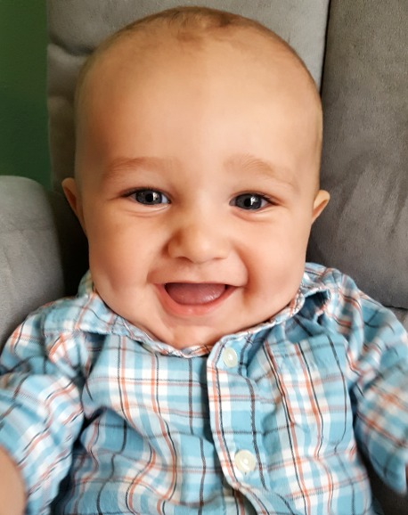 Happy baby boy in a blue plaid shirt