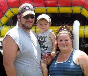 Adoptive couple Josh and Kristi with their son by a bounce house
