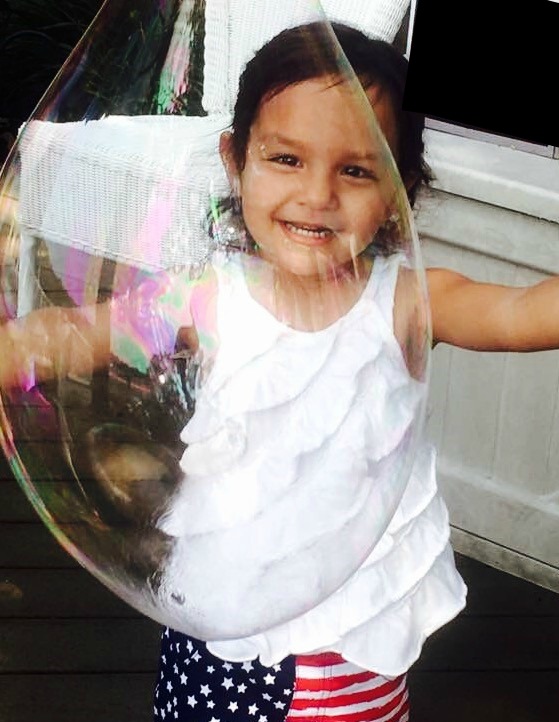 Small child smiling through a bubble that was blown