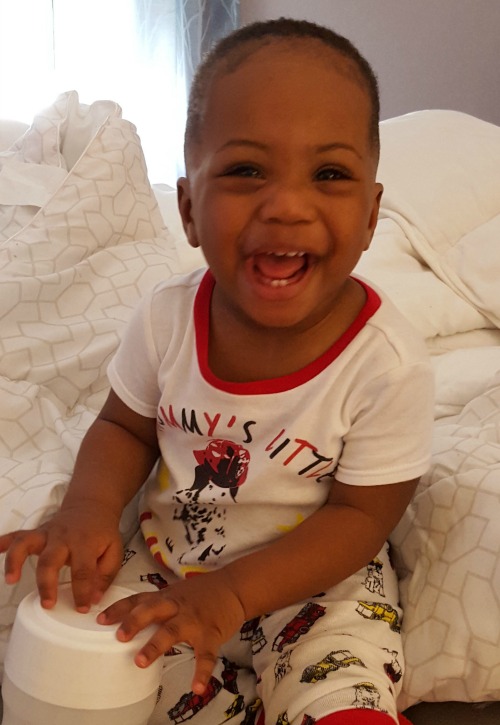 Black baby boy giggling on the bed