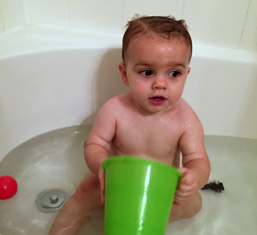 Baby in bath with green bucket