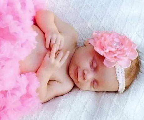 Baby girl in pink tutu and pink flower bow sleeping