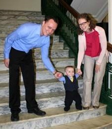 Adoptive parents Craig and Angela help their baby boy down the steps