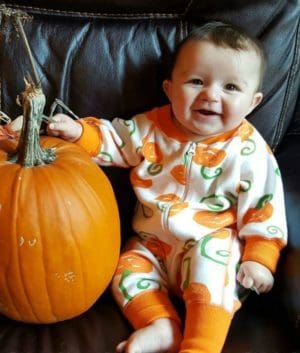 Adopted baby with pumpkin onesie and real pumpkin