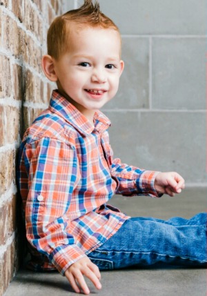 Smiling little boy leaning against a wall