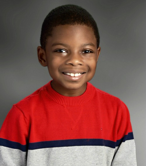 Portrait of a black boy in a red and gray sweater