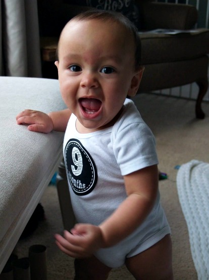 Happy baby boy in 9 months sticker holds himself up