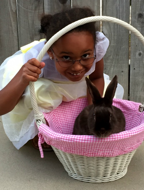 girl with glasses posing by bunny in basket