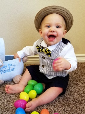 Adopted baby boy in bow tie and straw hat with Easter eggs