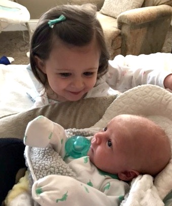 Big sister looks over newly adopted baby