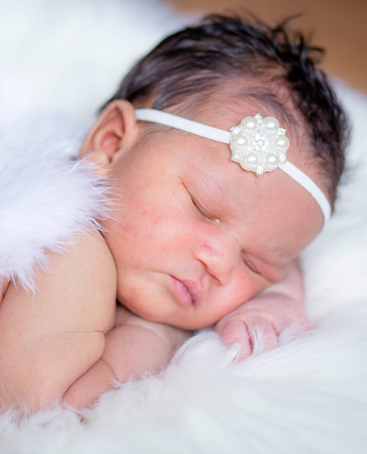 Sleeping baby girl in white headband and angel wings