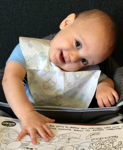 Baby in high chair with head tilted holding child's menu