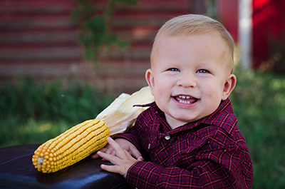 child smiling by corn cob