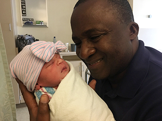 Happy adoptive dad admires his newborn daughter at the hospital
